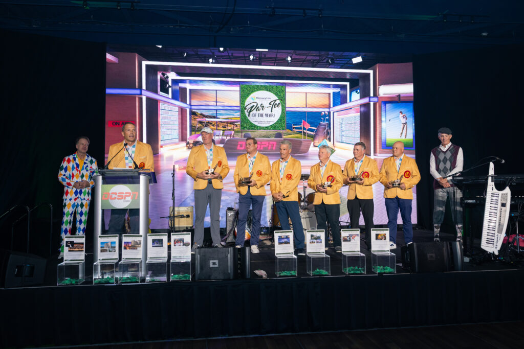 winners during charity gala standing up on stage with award of a golf club to fit with the event theme