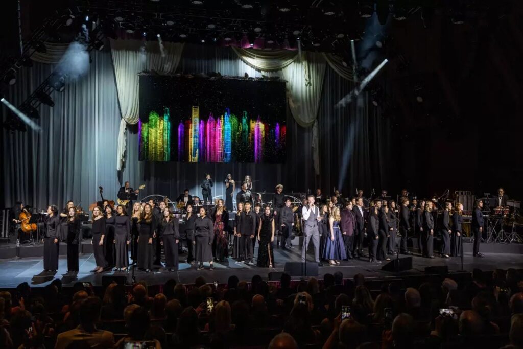 Hugh Jackman singing with the students on stage