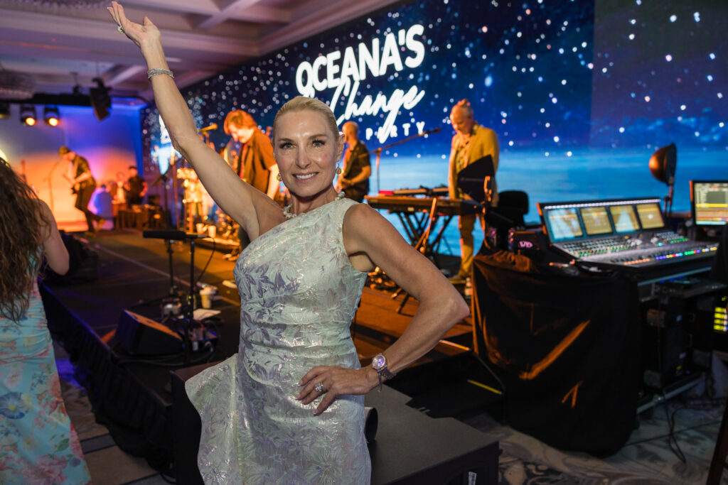 guest poses at fundraiser event in front of large screen