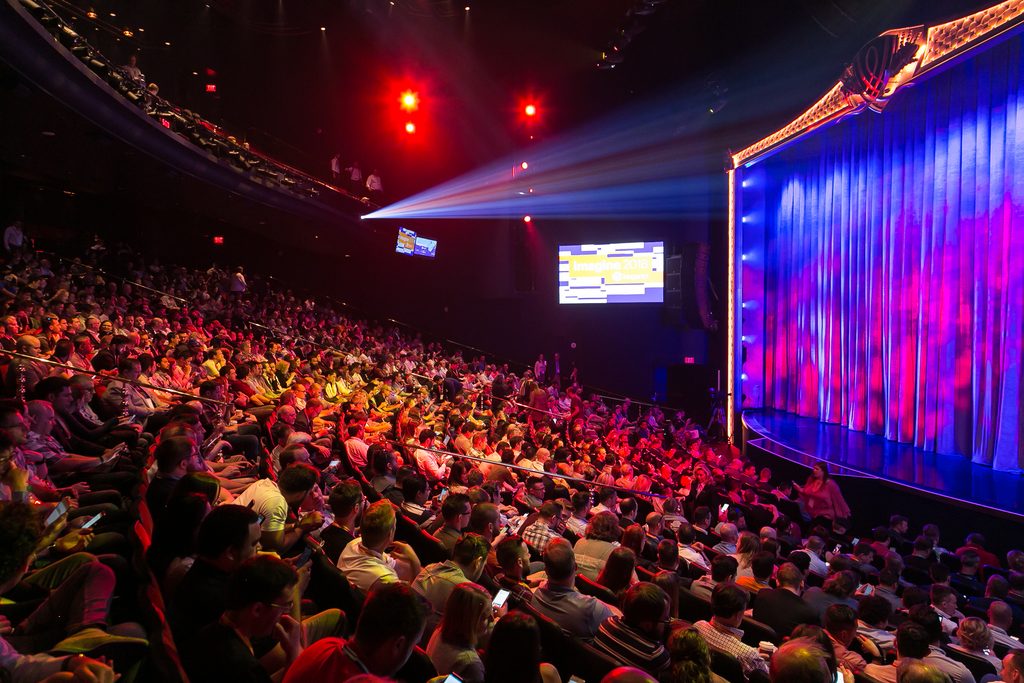 audience sits watching colorful stage at ecommerce conference