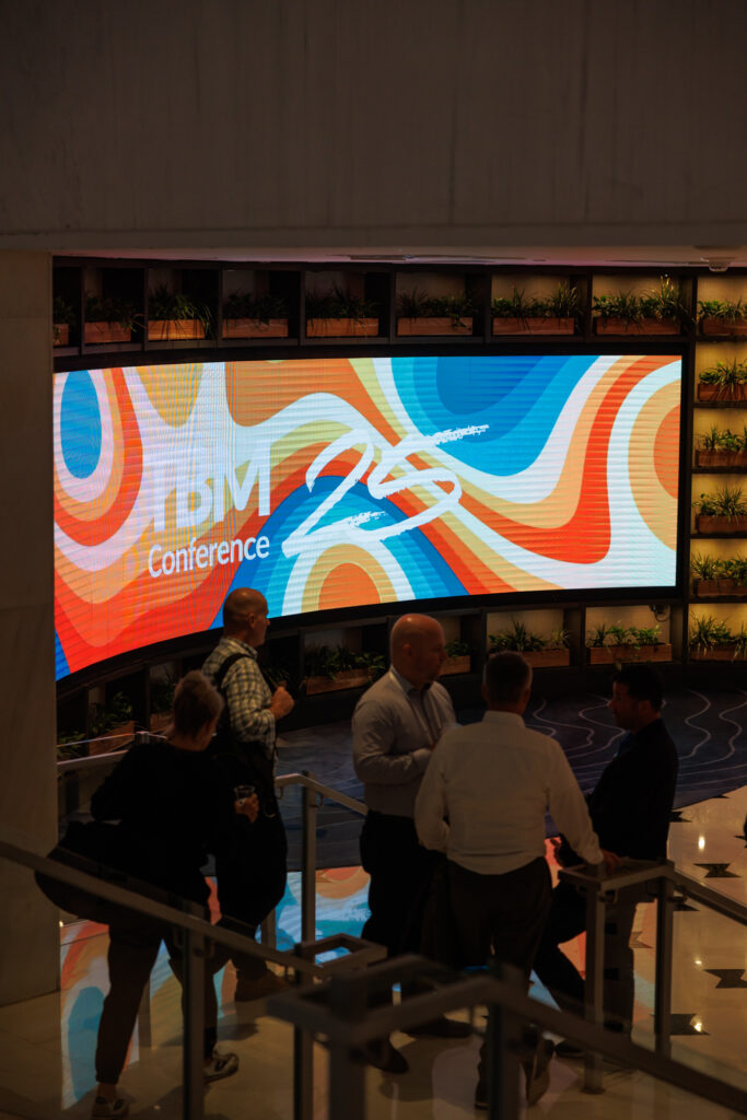 media design on screen while guests walk in to TBM Conference 2025